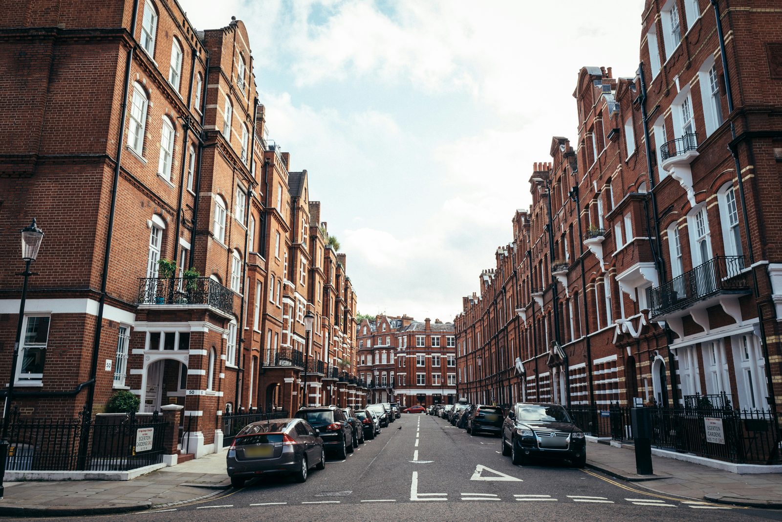Red-brick mansion blocks on both sides of a London street.